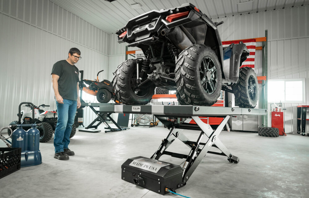 UTV on RAM lift in garage with person